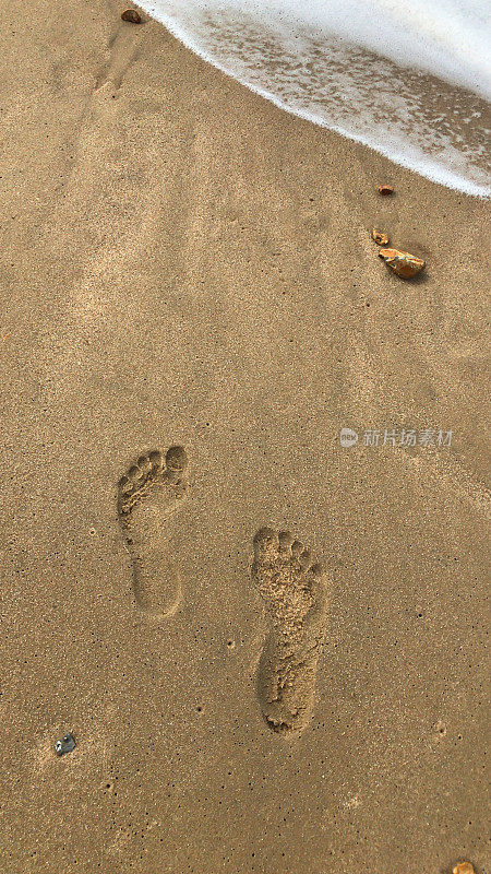 海滩脚印在潮湿的沙滩上的图像，赤脚走/光脚脚趾在海边沿果阿喀拉拉邦海滩，印度海岸线海，在夏天低潮的海浪，足迹足迹带领一个人走在印度海滩度假